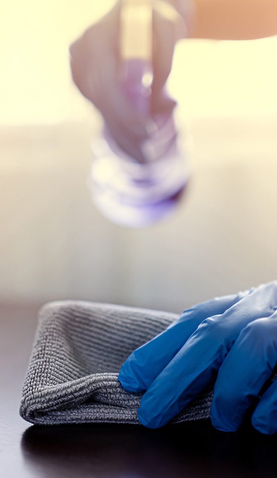 Hands wear blue rubber gloves to prevent germs and use disinfectant sanitizing spray cleaning table business office to disinfecting coronavirus and prevention against Coronavirus disease 2019, COVID